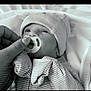 baby, infant, pacifier, hat, striped_clothing, hand, nail_art, blanket, bed, soft_lighting, black_and_white, cute, portrait, newborn, sleepwear, closeup, cozy, toddler, resting, comfort