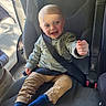toddler, child, car_seat, seatbelt, smiling, blue_eyes, blond_hair, sweater, pants, socks, car_interior, window, door, daylight, happy, portrait, sitting, baby, seatbelt_strap, playful
