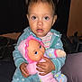 baby, blanket, bodypart, clothing, couch, cushion, doll, face, finger, furniture, hand, head, homedecor, pajamas, pants, person, photography, portrait, sitting, toy
