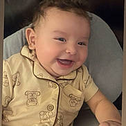 Erika joined the competition — help win amazing prizes! baby, child, infant, smiling, happy, portrait, sitting, leather_chair, couch, pajamas, teddy_bear_pattern, clothing, face, head, eyes, mouth, hand, indoor, home, closeup