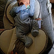 Dean is registered to the contest to win money with this photo: baby, pacifier, blue_onesie, infant, baby_rocker, cushion, hand, sleeping, indoor, soft_lighting, newborn, baby_clothes, baby_sleeping, baby_accessory, baby_bed, child, person, resting, cute, comfort