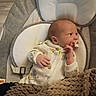 baby, infant, pacifier, onesie, blanket, baby_seat, cushion, sleepwear, newborn, child, indoor, cozy, knitted_blanket, cute, portrait, resting, hand, face, expression, clothing
