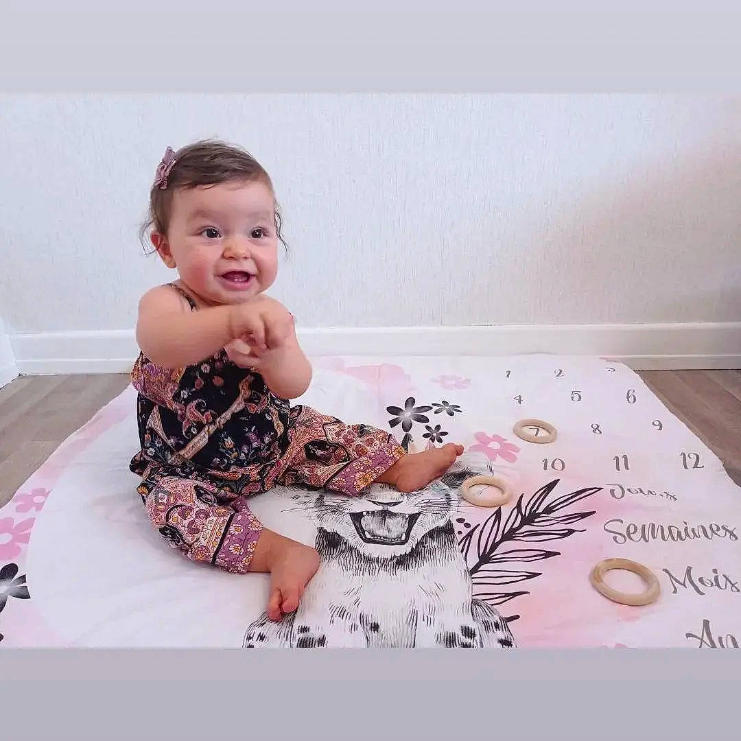 Mya participe au concours pour gagner de l'argent avec cette photo : baby, baby_toddler_clothing, child, comfort, day_dress, dress, fashion_design, finger, flooring, font, happy, linens, magenta, pattern, person, sitting, sleeve, smile, t_shirt, thigh