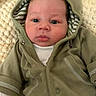 baby, infant, hoodie, green_clothing, blue_eyes, face, curly_hair, blanket, soft_texture, portrait, cute, child, newborn, indoors, wearing_clothes, closeup, resting, young, warm, cozy