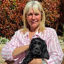 woman, dog, black_dog, pet, smiling, outdoor, garden, foliage, red_leaves, sunny, casual_clothing, striped_shirt, watch, sitting, lap, portrait, daylight, happy, nature, relaxing