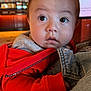 baby, child, face, red_jacket, denim_jacket, indoor, curious, wide_eyes, portrait, person, clothing, holding, cute, infant, warm_lighting, close_up, expression, young_child, soft_light, casual