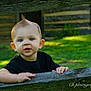 baby, black_shirt, blue_eyes, child, curious, daylight, fence, grass, greenery, hands, mohawk, nature, outdoor, person, photography, portrait, sunlight, toddler, wooden_fence, young_child
