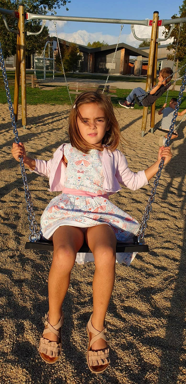Mila a rejoint le concours — aidez-le/la à gagner de superbes lots ! child, child_model, daughter, dress, fun, leg, outdoor_play_equipment, person, play, playground, public_space, recreation, sitting, smile, swing, thigh, tree