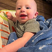 Clayton joined the competition — help win amazing prizes! baby, child, blanket, blue_blanket, baby_seat, indoor, happy, smiling, infant, person, floor, wooden_floor, furniture, cozy, cute, portrait, clothing, hand, face, young