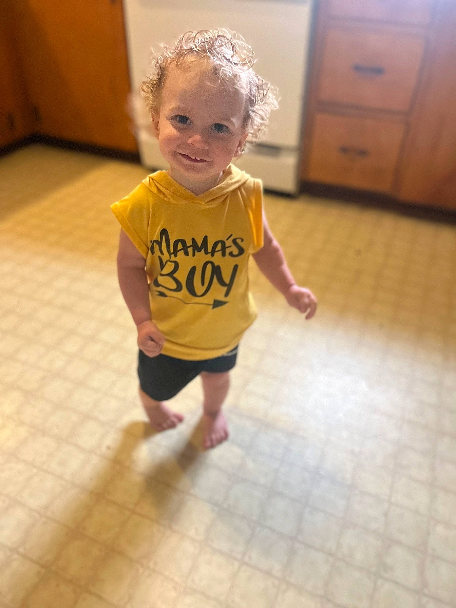 Sylas is registered to the contest to win money with this photo: baby, baby_toddler_clothing, barefoot, child, face, floor, flooring, hair, happy, hardwood, head, human_leg, joy, knee, person, skin, sleeve, smile, standing, t_shirt