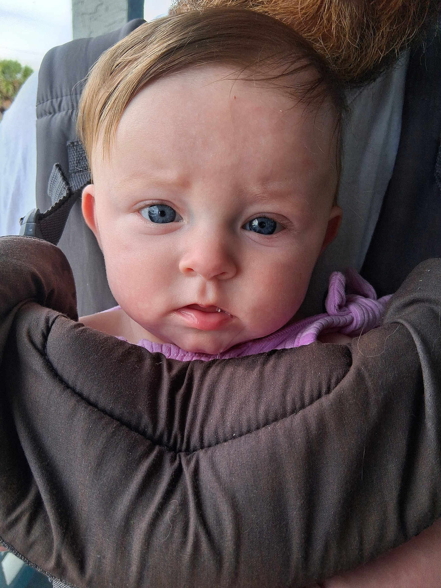 Feyre is registered to the contest to win money with this photo: baby, infant, face, blue_eyes, close_up, baby_carrier, purple_clothing, child, person, young, portrait, outdoor, human, skin, head, expression, cute, toddler, clothing, beard