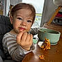 toddler, child, messy_face, eating, fork, food, high_chair, bowl, table, indoor, natural_light, striped_clothing, brown_hair, face, portrait, meal_time, cute, expression, hand, kitchen