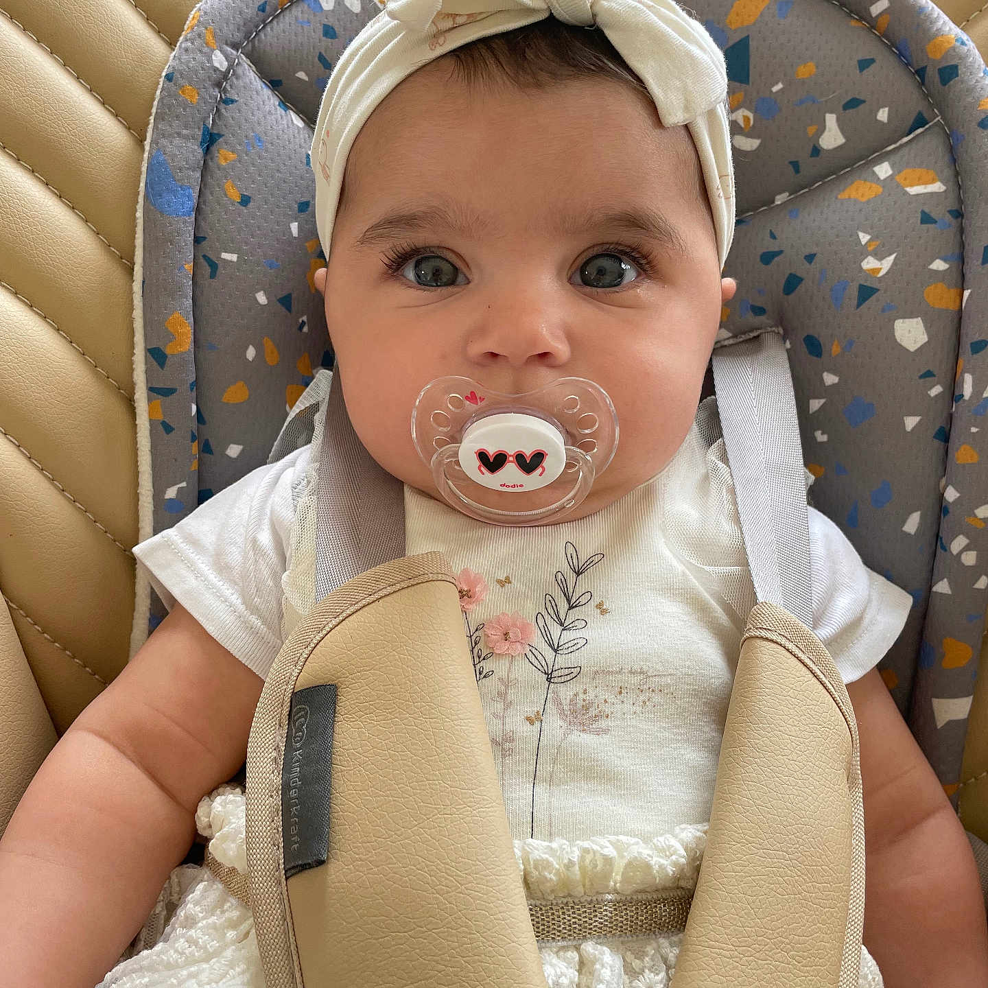 Lana participe au concours pour gagner de l'argent avec cette photo : adorable, baby, child, closeup, clothing, comfort, cute, expression, face, headband, indoor, infant, pacifier, patterned, portrait, seat, sitting, straps, white_dress, young