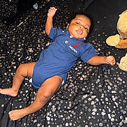 Kaden is registered to the contest to win money with this photo: baby, infant, child, blue_onesie, nautica, blanket, polka_dots, plush_toy, stuffed_animal, hairbrush, lying_down, skin, face, arm, foot, hand, curly_hair, indoor, soft_toy, fabric