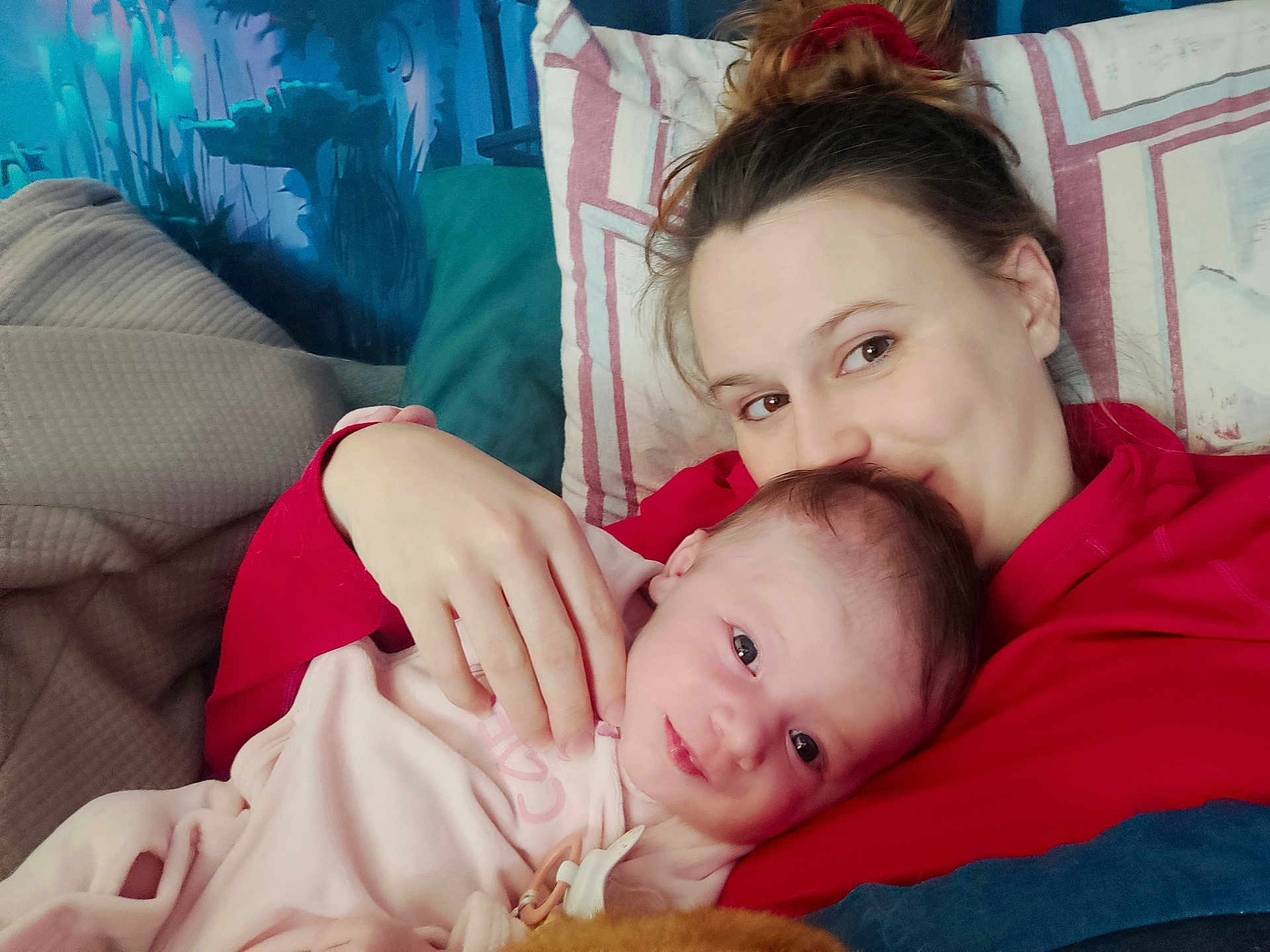 Loucya a rejoint le concours — aidez-le/la à gagner de superbes lots ! baby, woman, couch, pillow, red_hoodie, pink_clothing, face, hand, smile, indoor, cozy, portrait, child, love, family, relaxing, home, comfort, resting, casual