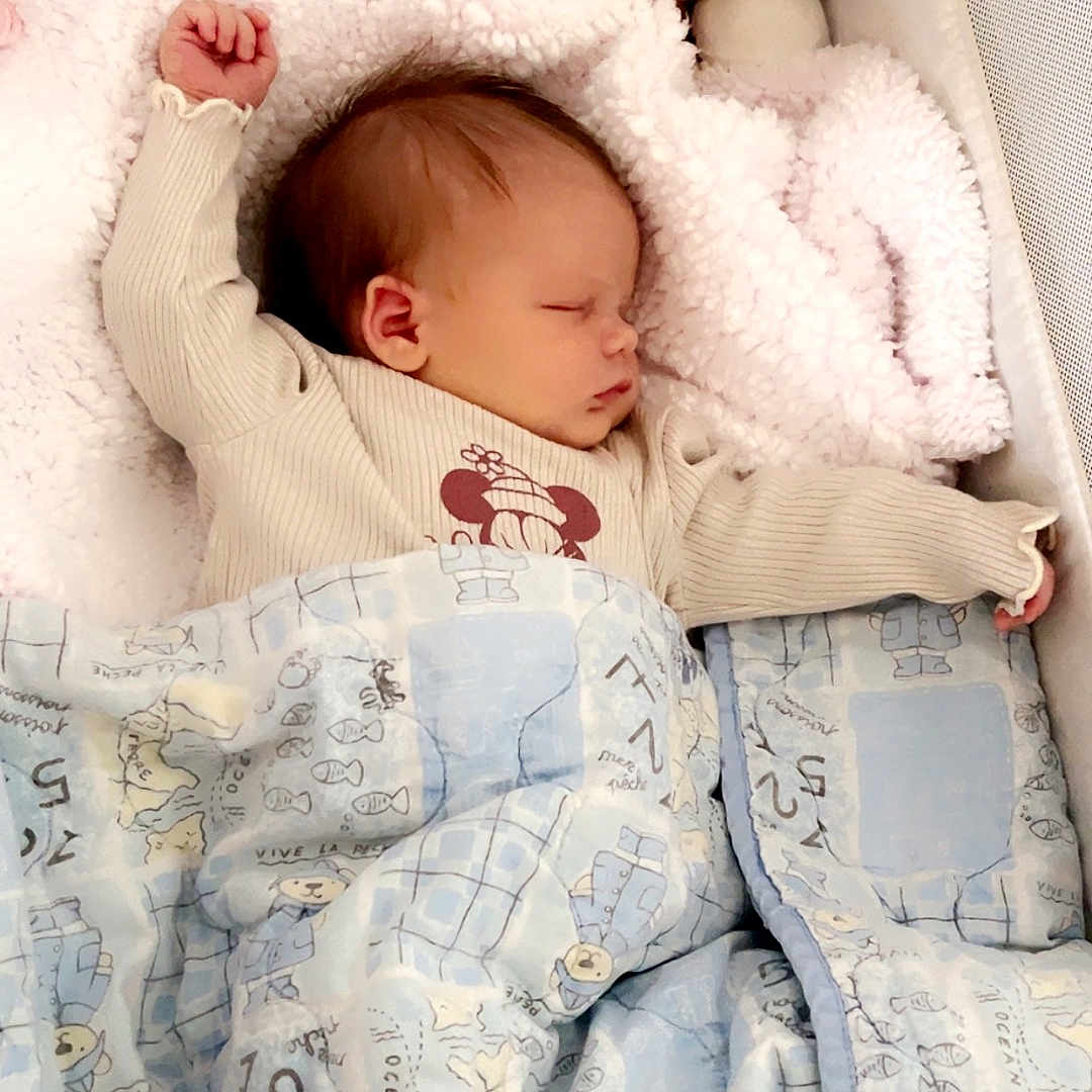 Maxine joined the competition — help win amazing prizes! baby, infant, sleeping, nap, portrait, child, face, closed_eyes, stretching, blanket, bedding, crib, plush_toy, stuffed_animal, indoors, cozy, peaceful, clothing, patterned_fabric, nursery