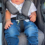 Carlos is registered to the contest to win money with this photo: toddler, baby, stroller, denim, white_shirt, sneakers, baby_bottle, child, seatbelt, cushion, clothing, footwear, person, portrait, indoor, cute, young_child, baby_accessory, casual_wear, sitting