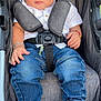 toddler, baby, stroller, denim, white_shirt, sneakers, baby_bottle, child, seatbelt, cushion, clothing, footwear, person, portrait, indoor, cute, young_child, baby_accessory, casual_wear, sitting