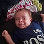 baby, blanket, bodypart, clothing, cushion, face, finger, furniture, hand, happy, head, homedecor, laughing, newborn, person, photography, portrait, quilt, smile, t_shirt
