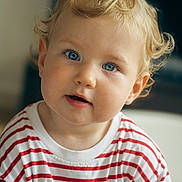 Raphaëlle a rejoint le concours — aidez-le/la à gagner de superbes lots ! baby, blonde_hair, blue_eyes, casual_clothing, child, close_up, curious, curly_hair, cute, expression, face, indoors, innocent, person, portrait, red_and_white, soft_light, striped_shirt, toddler, young_child