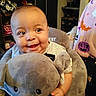 baby, infant, child, smiling, happy, portrait, close_up, indoors, plush_toy, whale, stuffed_animal, blanket, gray, seated, chair, casual_clothing, face, eyes, home, cozy