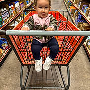 Elliana is registered to the contest to win money with this photo: toddler, child, shopping_cart, store_aisle, sneakers, jacket, hair_ties, curious, shopping, floor, shelf, products, cleaning_supplies, boxes, person, retail, indoor, grocery_store, baby, clothing