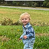 toddler, child, grass, outdoor, smiling, denim_overalls, blond_hair, nature, trees, greenery, lawn, happy, walking, person, casual_clothing, phone_screen, mobile_interface, app_icons, google_search_bar, daytime