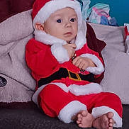 Thomas joined the competition — help win amazing prizes! baby, child, santa_claus_outfit, red_clothing, white_fur_trim, couch, blanket, indoor, feet, sitting, cute, holiday, christmas, infant, person, face, expression, cozy, furniture, soft