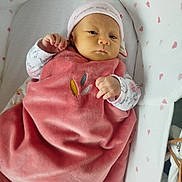 Lou a rejoint le concours — aidez-le/la à gagner de superbes lots ! baby, infant, blanket, pink, hat, bassinet, heart_pattern, clothing, sleeping_bed, cute, newborn, soft_texture, child, indoors, resting, portrait, cozy, wrapped, young, peaceful