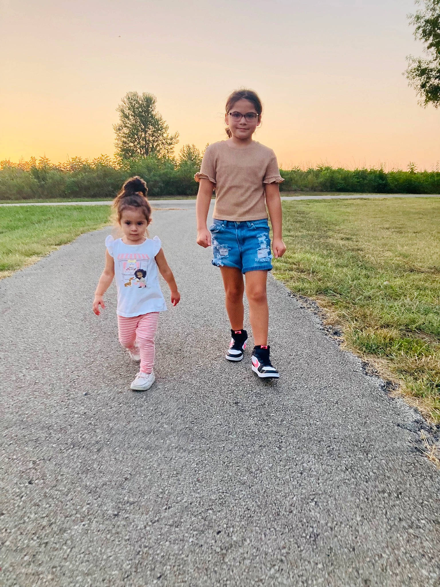 Arya is registered to the contest to win money with this photo: asphalt, footwear, fun, gesture, grass, grass_family, grassland, happy, holding_hands, horizon, joy, landscape, leisure, people_in_nature, person, plant, road, shorts, sky, t_shirt