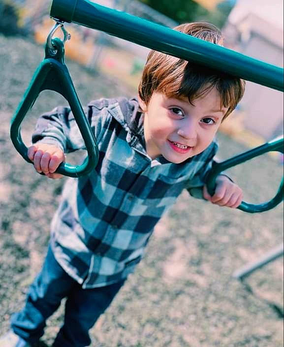 Carlos is registered to the contest to win money with this photo: child, city, face, fun, grass, happy, joy, leisure, outdoor_play_equipment, outdoor_recreation, pattern, people_in_nature, person, plaid, play, playground, recreation, smile, swing, t_shirt