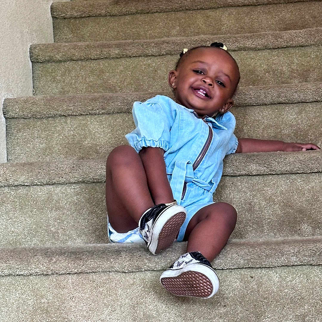 Amya is registered to the contest to win money with this photo: architecture, building, child, clothing, face, female, footwear, girl, happy, head, house, housing, pants, person, photography, portrait, shoe, shorts, sitting, staircase