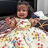 Imrat is registered to the contest to win money with this photo: child, toddler, dress, colorful, polka_dot, smiling, happy, person, bed, blanket, clothing, bracelet, hair, indoor, furniture, head, cute, portrait, baby, room