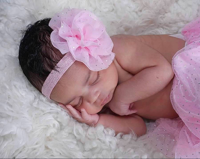 Jazmin is registered to the contest to win money with this photo: arm, baby, baby_sleeping, baby_toddler_clothing, cap, comfort, eyebrow, finger, head, headband, headgear, headpiece, headwear, linens, lip, nail, person, petal, pink, plant
