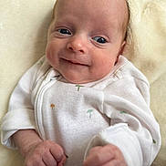 Bryson is registered to the contest to win money with this photo: baby, infant, smile, face, fist, onesie, clothing, blanket, soft, cute, portrait, newborn, skin, happy, child, person, lying_down, indoors, closeup, expression