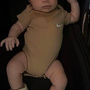 Shiloh is registered to the contest to win money with this photo: baby, infant, clothing, onesie, booties, nike, pacifier, lying_down, serious_face, skin, person, apparel, footwear, infant_clothing, baby_accessory, indoors, portrait, human, cute, child