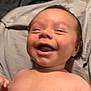 baby, smiling, happy, infant, shirtless, lying_down, blanket, pillow, monkey_pattern, soft_texture, closeup, cute, child, skin, face, expression, indoors, comfort, joy, playful