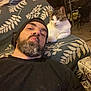 Croquette a rejoint le concours — aidez-le/la à gagner de superbes lots ! animal, beanie, black_shirt, casual, cat, couch, cozy, curious, facial_hair, furniture, home, indoor, living_room, man, patterned_fabric, pet, portrait, relaxed, seated, table