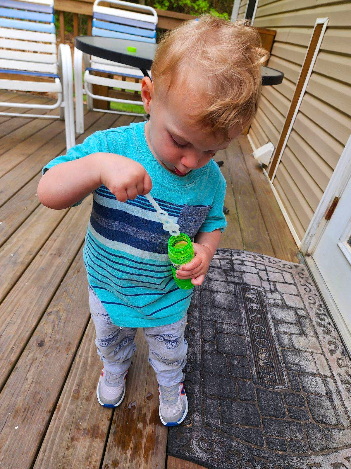 Kyler joined the competition — help win amazing prizes! baby, baby_toddler_clothing, child, deck, flooring, fun, grass, green, hair, hardwood, leisure, outdoor_furniture, pattern, people_in_nature, person, sitting, t_shirt, toddler, tree, wood