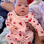 Amaya is registered to the contest to win money with this photo: baby, infant, pink_clothing, red_hearts, headband, red_bow, hand, blanket, person, indoor, cute, sleepwear, cozy, soft, portrait, child, newborn, sitting, family, comfort