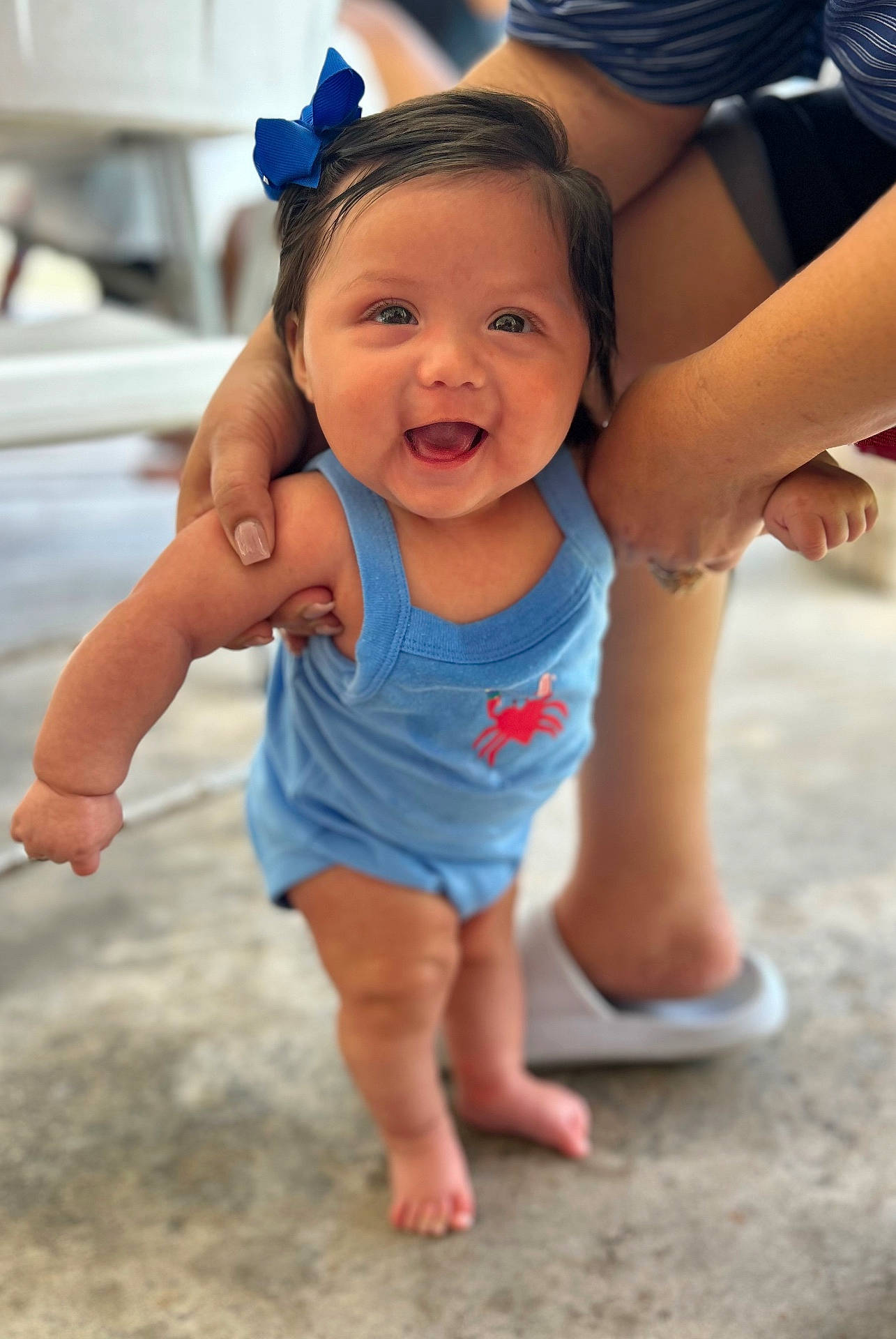Aleiya is registered to the contest to win money with this photo: baby, barefoot, blue_bow, blue_romper, child, concrete_floor, crab_design, cute, early_steps, face, hands_supporting, happy, head, human, infant, outdoor, person, portrait, smiling, walking