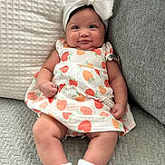 Aleiya joined the competition — help win amazing prizes! baby, bow, child, chubby_cheeks, couch, cozy, cute, dress, fruit_pattern, happy, headband, indoors, infant, pillow, portrait, relaxing, seated, smile, texture, white_socks