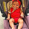 accessory, baby, baby_girl, car_seat, child, chubby_cheeks, closeup, cute, flower, happy, headband, indoor, infant, pacifier, person, portrait, purple, red_clothing, seat_belt, smiling
