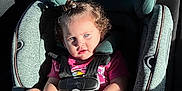 Hannah joined the competition — help win amazing prizes! toddler, child, car_seat, seatbelt, curly_hair, blue_eyes, sunlight, vehicle_interior, sitting, pink_shirt, baby, young_child, safety_harness, car, portrait, cute, serious_expression, indoor, person, daylight