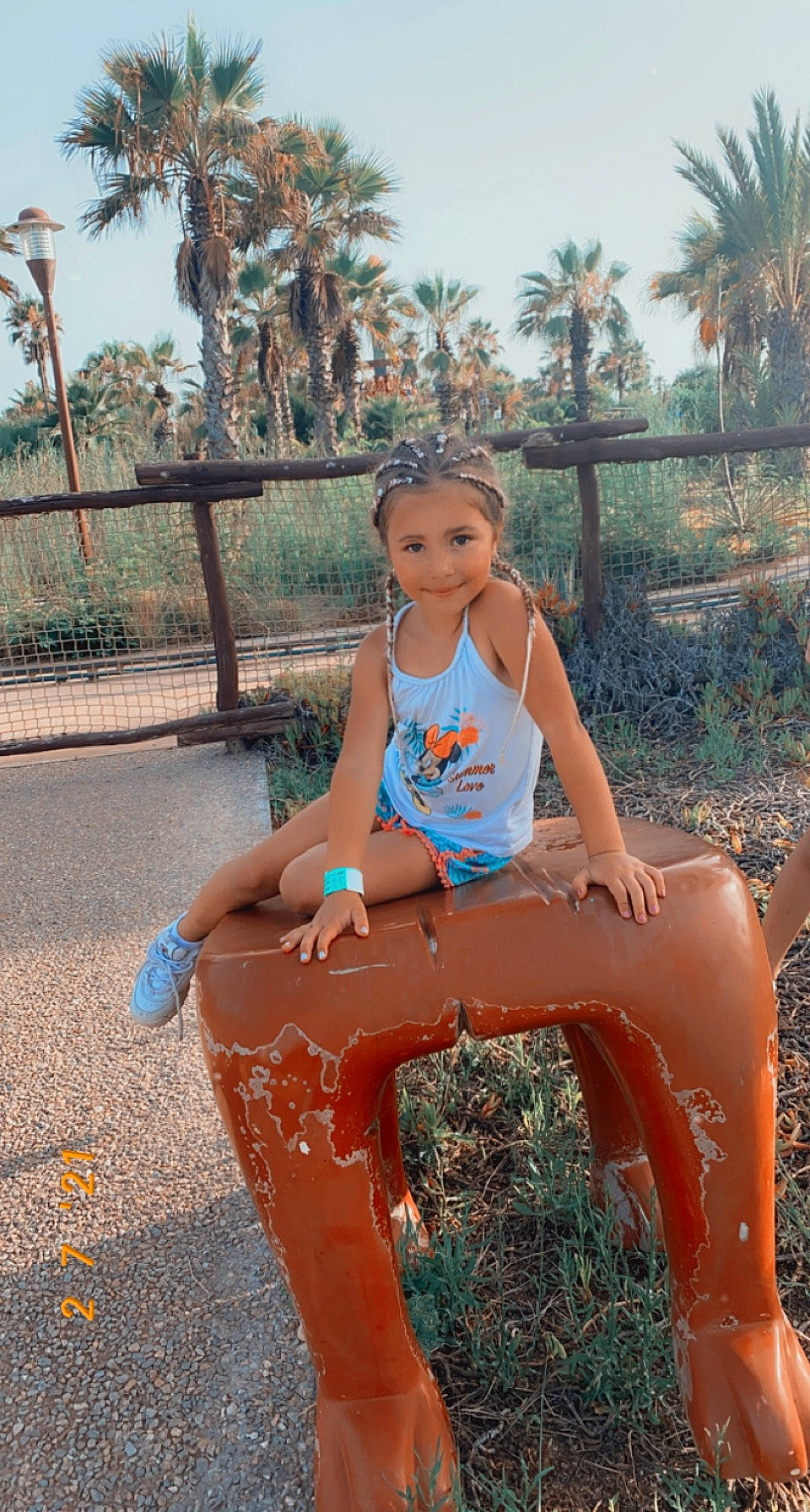 Lilya a rejoint le concours — aidez-le/la à gagner de superbes lots ! arecales, barefoot, black_hair, child, electric_blue, face, fun, happy, headwear, human_leg, joy, leg, leisure, outdoor_play_equipment, palm_tree, person, plant, recreation, sky, t_shirt