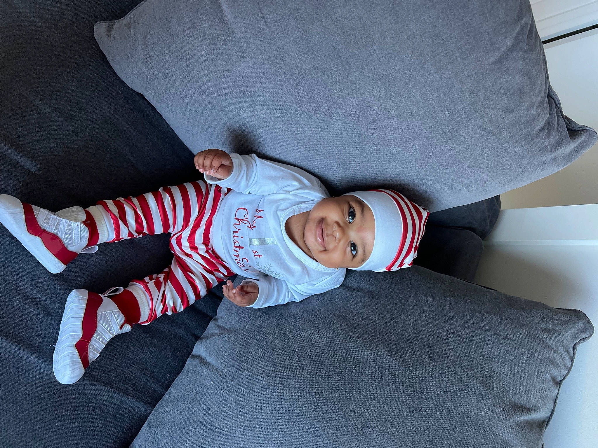 Zahria is registered to the contest to win money with this photo: baby, baby_products, baby_toddler_clothing, carmine, child, comfort, couch, hat, headwear, joy, linens, person, room, sitting, sleeve, smile, suit, t_shirt, toddler, tree
