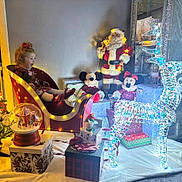 Jessica is registered to the contest to win money with this photo: child, girl, christmas, sleigh, lights, reindeer, santa, plush_toy, mickey_mouse, minnie_mouse, presents, holiday, decorations, snow_globe, carpet, excitement, indoor, festive, smile, celebration