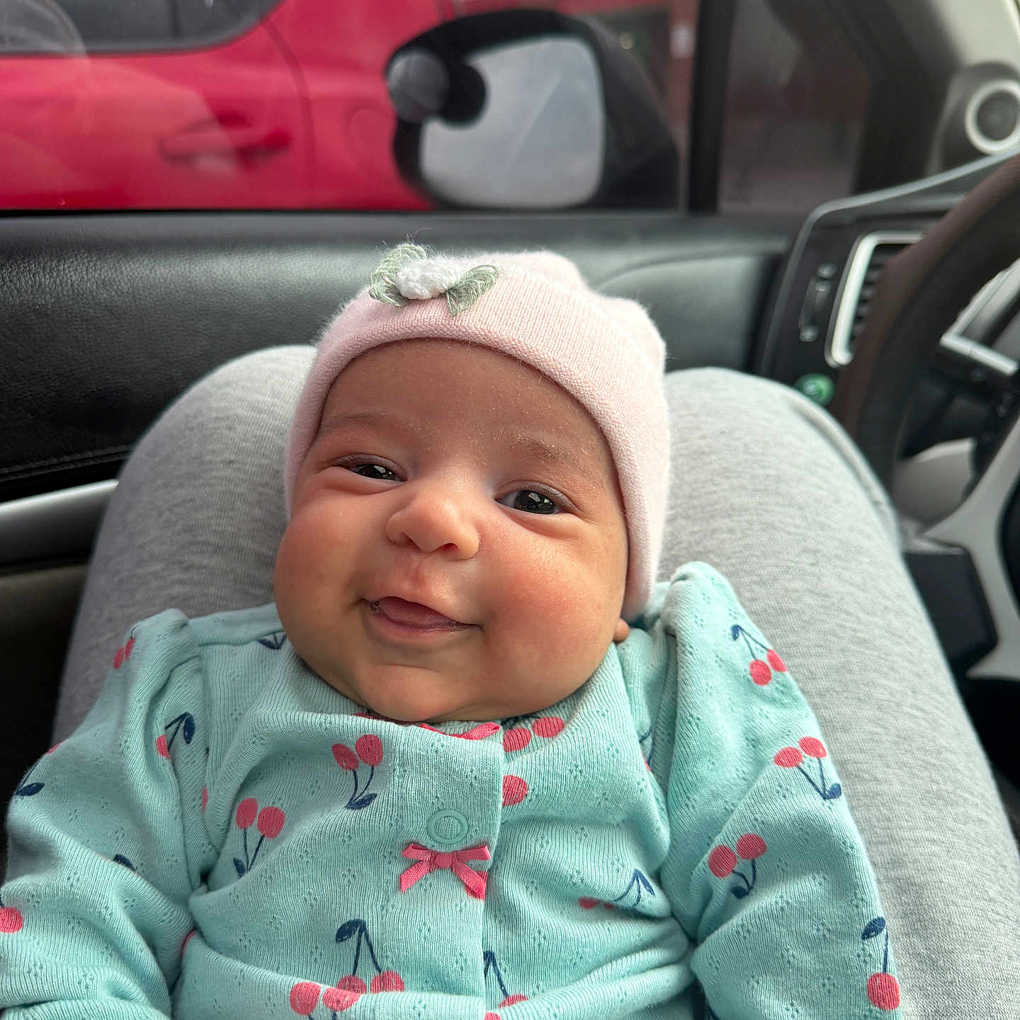 Dionatan is registered to the contest to win money with this photo: baby, car_interior, cherry_pattern, child, clothing, cute, door, face, happy, hat, infant, lap, onesie, person, portrait, red_car, seat, side_mirror, smile, window