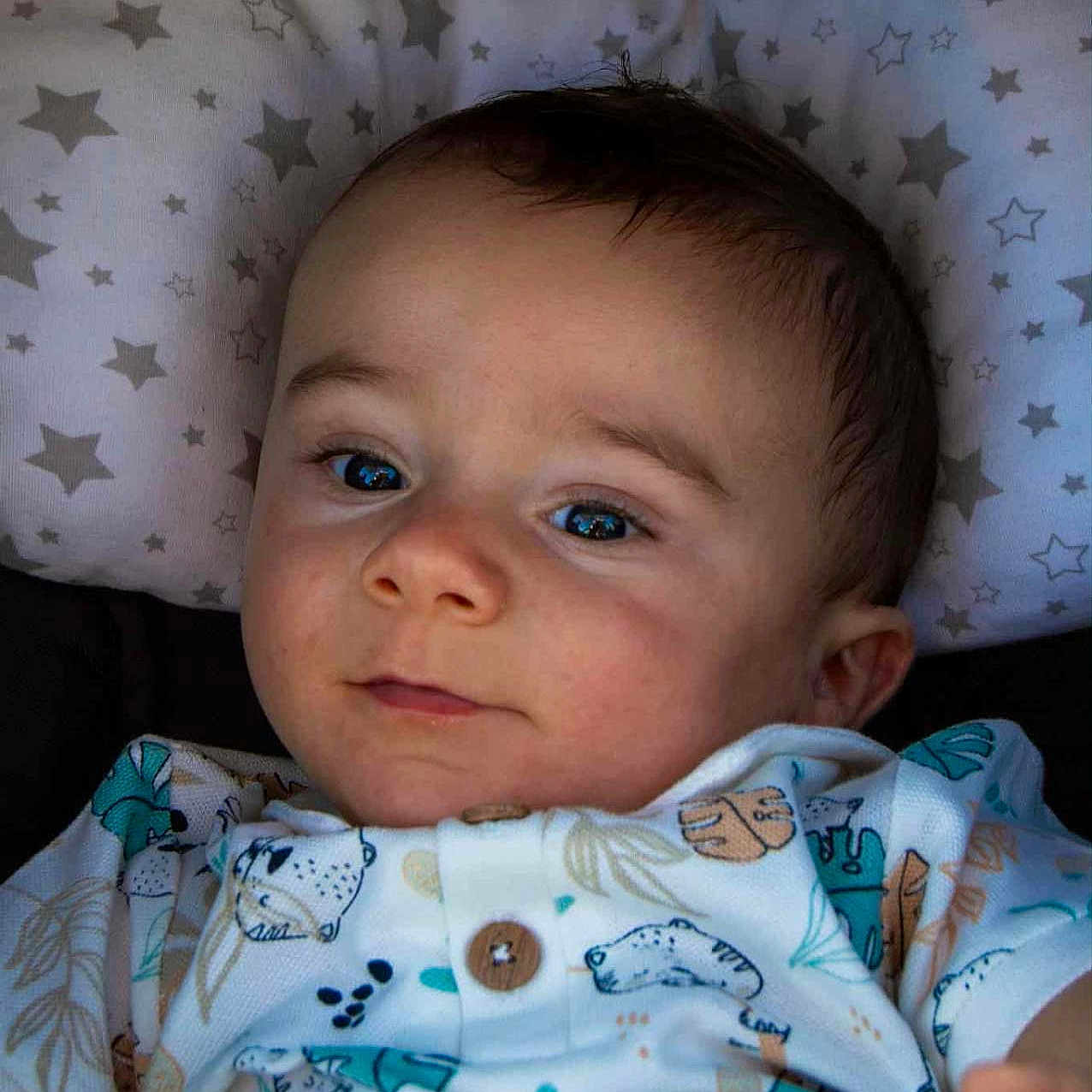 Noah participe au concours pour gagner de l'argent avec cette photo : animal_print, baby, button, child, clothing, cute, face, indoors, infant, looking_at_camera, lying_down, pattern, pillow, portrait, short_sleeve, skin, smile, soft_lighting, stars, young