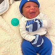 Daylen joined the competition — help win amazing prizes! baby, infant, smiling, blue_hat, mittens, pacifier, blanket, white_shirt, blue_pants, nike_logo, cozy, happy, lying_down, indoor, cute, child, face, clothing, soft_texture, relaxed
